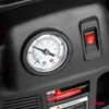 A close-up view of a pressure gauge and a red switch on a black surface. Podgląd zdjęcia produktu
