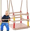 A baby sitting on a wooden swing. Produktbild-Vorschau