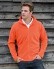 A man wearing a fleece jacket and jeans, leaning against a wooden wall. Produktbild-Vorschau