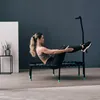 A woman is exercising on a trampoline indoors. Voir les images du produit