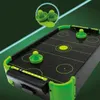 A close-up, angled view of a mini air hockey table with neon green accents and pucks. Náhľad obrázku produktu