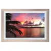 A framed picture of a sunset over the ocean with a palm tree in the foreground. Produktbild-Vorschau