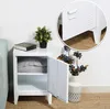 A white metal nightstand with an open door, revealing two gray pillows inside. A book and a potted plant sit on top of the nightstand. A vase with blue berries is placed next to it. A close-up inset shows the door handle and ventilation slits. Anteprima dell’immagine prodotto