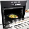 An open oven with a pan of vegetables on the rack. Voir les images du produit