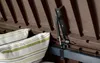 Close-up view of the interior of a brown storage box, showing a gas strut mechanism and a striped cushion. Podgląd zdjęcia produktu