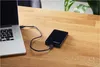 A black external hard drive connected to a laptop on a wooden desk. Produktbild-Vorschau