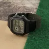 A digital watch with a black case and green fabric strap is placed on a textured surface with brown and green sections. Produktbild-Vorschau