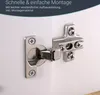 A close-up view of a cabinet hinge attached to two white cabinet doors, with German text overlay at the top. Produktbild-Vorschau