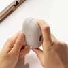 Hands holding a gray charging case for wireless earbuds. Produktbild-Vorschau