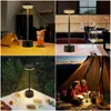 A collage of four images showing a portable LED table lamp in different settings: on a table with a drink, on a table in a restaurant, on a table outdoors, and inside a tent with people. Náhľad obrázku produktu