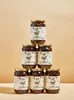 A pyramid stack of six jars of Kalamata olives against a light brown background. Produktbild-Vorschau