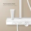 A close-up view of a modern white shower system with a glass shelf and a tube of product on it. Anteprima dell’immagine prodotto