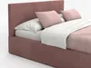 A close-up shot of a pink upholstered bed with pillows and a white blanket. Produktbild-Vorschau