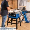 A person is using a blue table saw in a workshop setting. Produktbild-Vorschau