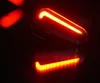 A close-up shot of a red and orange bicycle light reflecting on a dark surface. Podgląd zdjęcia produktu