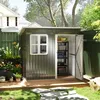 A garden shed filled with storage items, set in a backyard with plants and a house in the background. Produktbild-Vorschau