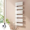 A white electric towel radiator mounted on a light pink wall next to a window with greenery visible outside. Voir les images du produit