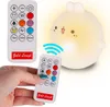 A hand holding a remote control pointing at a glowing bunny-shaped night light. Produktbild-Vorschau