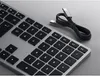 A close-up view of a silver keyboard with black keys and a black USB-C cable coiled next to it. Podgląd zdjęcia produktu