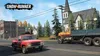 A red pickup truck and a yellow and blue truck drive on a road in front of a church and buildings. Produktbild-Vorschau