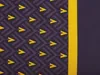 A close-up of a dark purple and yellow patterned fabric, likely bedding, with a solid yellow stripe on the right side. Náhled obrázku produktu