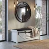 A white storage bench with a black cushion and a knitted throw is placed in an entryway with a large round mirror above it. Podgląd zdjęcia produktu