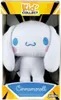 A Cinnamoroll plush toy is displayed in its retail packaging, which features a yellow and black striped design at the top and a blue banner at the bottom with the product name. Produktbild-Vorschau