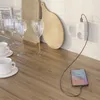 A smart plug is charging a smartphone on a kitchen counter. Náhľad obrázku produktu