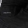 A close-up view of a black denim pocket with a brand logo. Produktbild-Vorschau