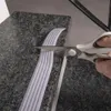 A person is cutting a strip of anti-slip tape with scissors on a granite surface. Náhled obrázku produktu