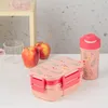 A pink floral lunchbox and a matching water bottle are displayed on a white surface, with two apples and a glass in the background. Podgląd zdjęcia produktu