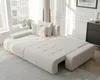 A modern, beige L-shaped sofa with a tufted design, shown in a well-lit living room with large windows. Produktbild-Vorschau