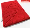 A red bath mat with a leaf-like texture is shown from a diagonal angle on a white background. Produktbild-Vorschau