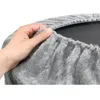 A hand is shown holding and demonstrating the soft, plush fabric of a grey cover for a round pet bed or similar item. Produktbild-Vorschau