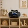 A black boombox sits on a wooden shelf next to a stuffed bunny and a wooden elephant. The shelf is part of a larger shelving unit with other decorative items. Produktbild-Vorschau