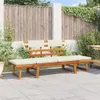 A wooden garden bench with beige cushions sits on a paved patio, with a wooden fence and greenery in the background. Voir les images du produit