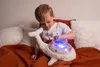 A young boy is sitting on a bed with a plush whale toy that has lights. Anteprima dell’immagine prodotto