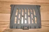 A cast iron grate for a fireplace or stove is placed on a wooden surface. Podgląd zdjęcia produktu