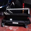 A person's legs and a black toolbox with tools are visible. Voir les images du produit