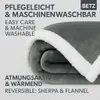 A folded gray blanket with a white sherpa trim is shown against a light gray background. Text overlays describe the product's features. Produktbild-Vorschau