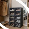 A stack of shoe boxes filled with shoes, placed in a closet next to hanging clothes. Podgląd zdjęcia produktu