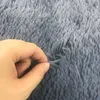 A hand is shown pinching a piece of a gray shaggy rug. Náhled obrázku produktu