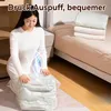 A woman is kneeling on the floor, using a vacuum bag to compress bedding. A bed with folded blankets is visible in the background. Produktbild-Vorschau
