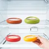 Four food storage containers are placed on shelves inside a refrigerator. A hand is reaching for one of the containers. Produktbild-Vorschau