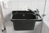 A black sink with a chrome faucet mounted on a tiled wall. Anteprima dell’immagine prodotto