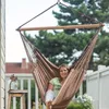 A woman is relaxing in a brown hammock chair on a balcony. Produktbild-Vorschau