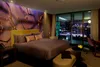 A luxurious hotel bedroom with a large window overlooking a city skyline at night. Voir les images du produit