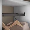 A close-up view inside a wardrobe, showing a dark metal hanging rail with two hangers holding a beige jacket. Anteprima dell’immagine prodotto