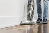 A person is using a BISSELL CrossWave vacuum cleaner to clean a floor near a wall. Voir les images du produit