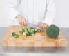 A person in a white chef's coat is chopping broccoli on a wooden cutting board. Anteprima dell’immagine prodotto